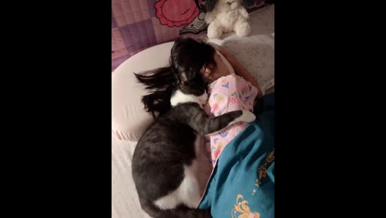 Sleepy cat cuddles up beside sleeping girl in Guangdong, China