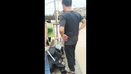 Man catches massive fish with net as people gather by river in Zhejiang, China