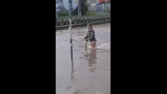 Girl rides scooter through flooded Moscow road