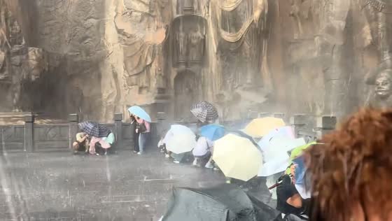 Tourists struggle to stay upright during severe storm at Longmen Grottoes in Luoyang, Henan, China