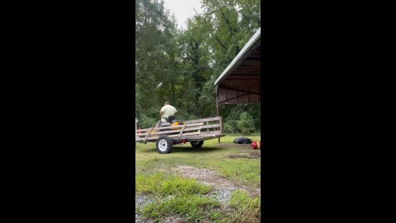 Man struggles to load lawn mower onto trailer in Smithfield, Virginia, USA