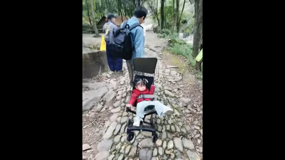 Child endures bumpy stroller ride on rocky path in Zhejiang, China