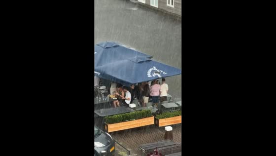Rainstorm rolls through, soaking busy outdoor terrace in Amsterdam, the Netherlands