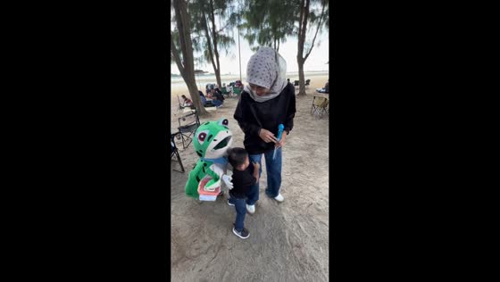 Person in frog costume teases child in Malacca, Malaysia