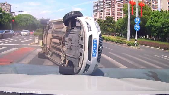 Car flips sideways and nearly hits dashcam vehicle at intersection in Jiangsu, China