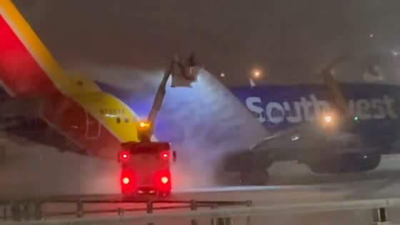 Southwest aircraft de-iced during nighttime snowfall in Rochester, New York, USA