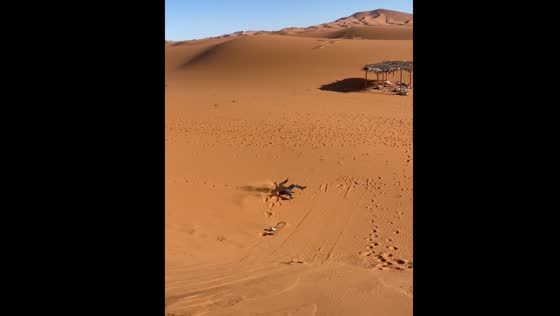 Person falls while sliding down sand dune in Merzouga