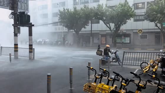 Deliveryman struggles to move motorcycle during severe rainstorm in Shanghai, China