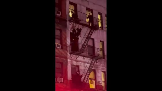 NYPD officers detain man on fire escape in Manhattan, New York, USA