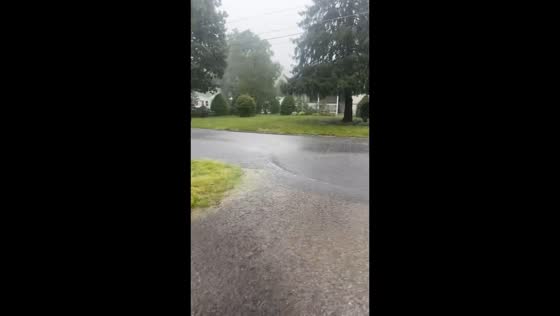 Floodwater rushes across street during heavy rain in Rancocas, USA
