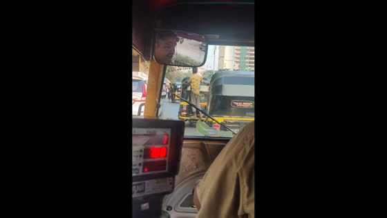 Person hangs on the back three-wheel vehicle in Mumbai, India