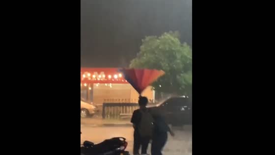 Umbrella mishap sends friends running in the rain in Riau, Indonesia