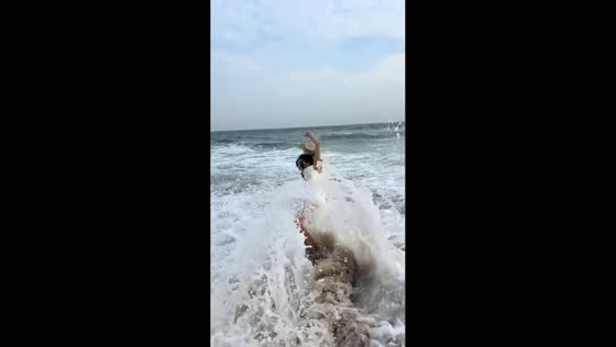 Unexpected wave knocks woman into water at beach in Jiangsu, China