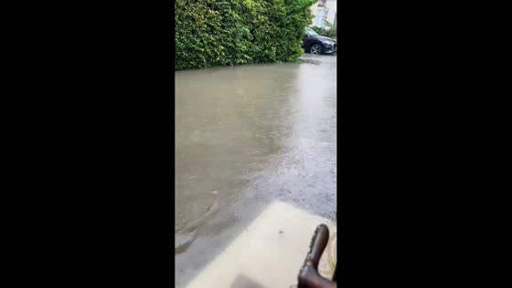 Delivery rider wades through floodwater during heavy rain in Shanghai, China