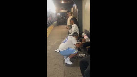 Woman casually grooms dog at Gates Ave train station in Brooklyn, New York, USA
