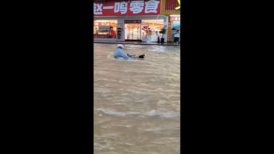 Man clings to motorcycle as floodwaters sweep across road in Putian, China