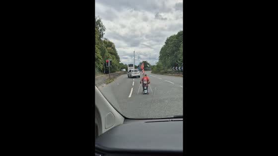 Man rides mobility scooter along road in Warrington, England, UK