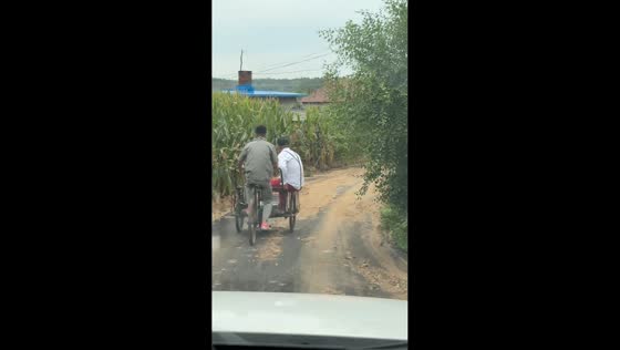 Two men fall from a trike on a rough road in Liaoning, China