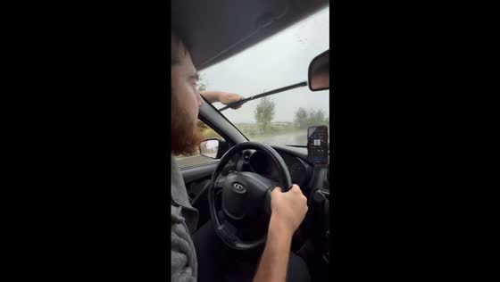 Driver manually wipes windshield during heavy rain in Makhachkala, Russia