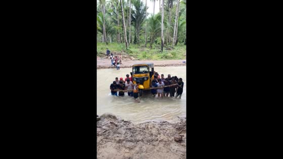 Locals rally: carrying a vehicle across flooded river after bridge collapse