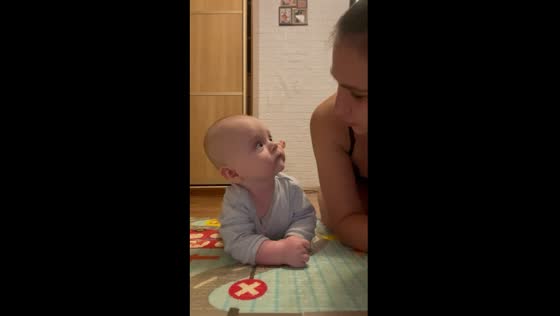 Captivating connection: mother and infant lock eyes in heartwarming tummy time moment
