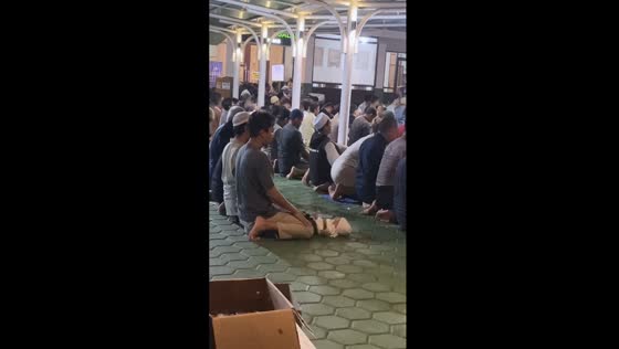 Touching act of devotion: father balances prayer and parental duty in Surabaya, Indonesia