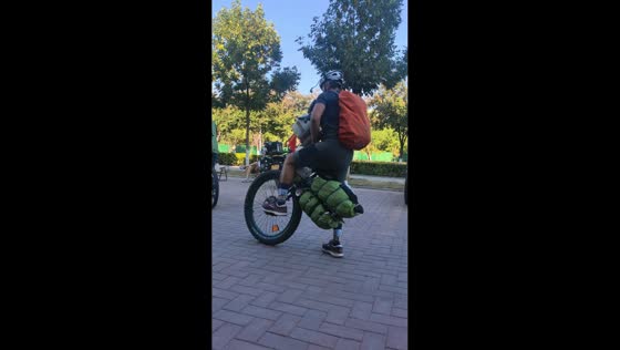Man rides loaded unicycle through street in Xinjiang, China