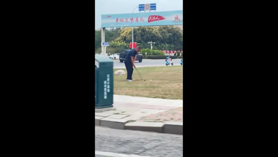 Man casually plays golf by the roadside in Tianjin, China