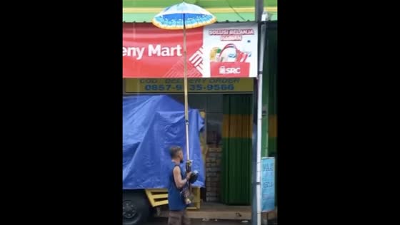 Hilarious moment caught on camera: Man uses giant umbrella in Ngawi rain