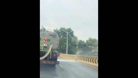 Dog enjoys spray from water truck while running alongside road in Jiangxi, China