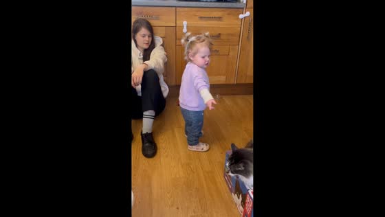 Cute toddler playfully talks to older sister in Wales, UK