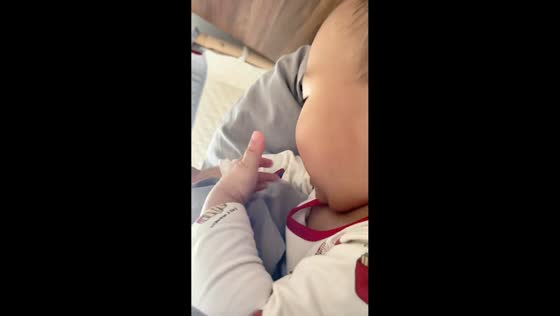 Toddler tries to “eat” shirt print while lying on a bed in Fujian, China.