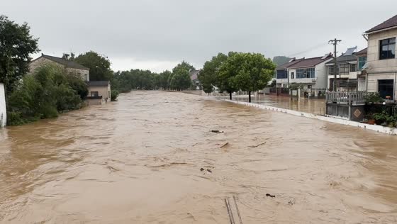 Rushing muddy floodwaters cover residential street in Jiangsu, China