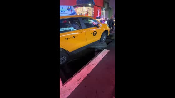 Taxi falls through service vault grate in Times Square, New York, USA