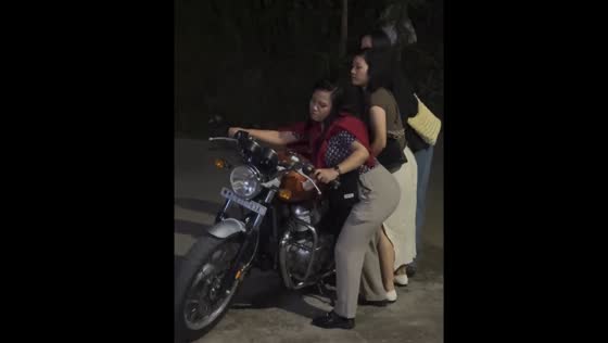 Three ladies struggle to move motorcycle in Aizawl, Mizoram, India
