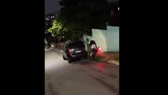 Bike loses balance and hits parked car on downhill road in Brazil