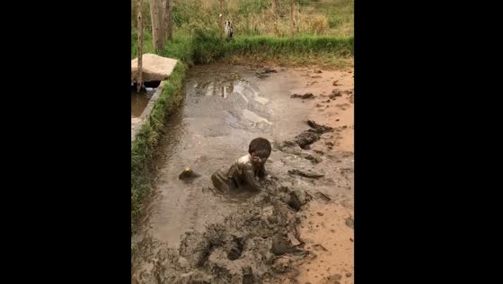 Child jumps and plays in muddy water in Buenos Aires