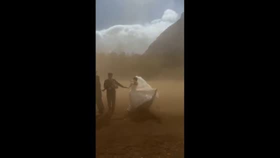 Wedding couple stands in strong wind and dust storm in Hainan, China
