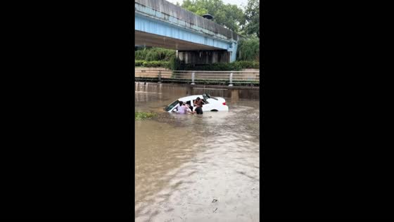 People rescue occupants stranded in a car amid heavy flooding in Changxing, China