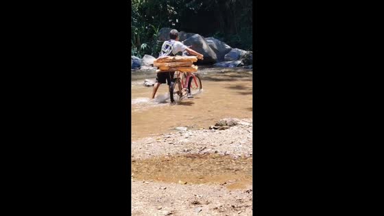 Boy and dog carefully cross stream with bicycle in Sendero La Montañita, Argentina