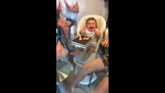 Toddler looks mad while blowing birthday candle in Madrid, Spain