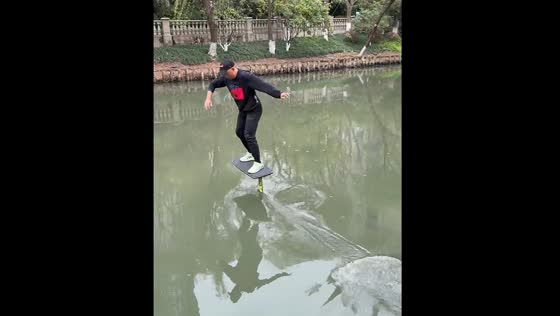 Person surfs on inner city river in Hangzhou with hydrofoil board