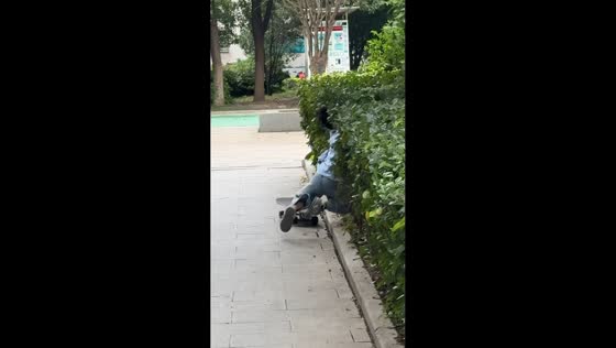 Boy on skateboard tumbles into bushes at park in Hubei, China