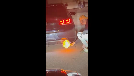 Man lights a cigarette using car exhaust flames in Porto, Portugal