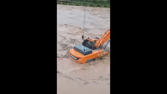 Excavator operator navigates floodwaters to move trapped machine in Hunan, China