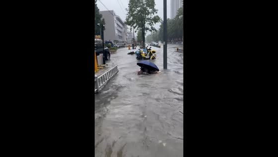 Pedestrian falls twice on flooded street in Zhejiang, China