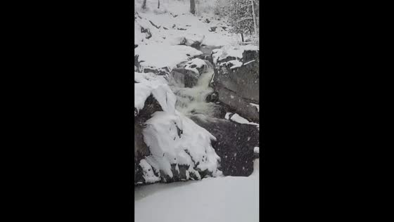 Mesmerizing winter scene as river flows amidst heavy snowfall in Byron, Maine