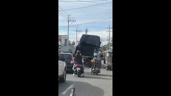 Riders avoid truck with unstable metal cargo in Manila, Philippines