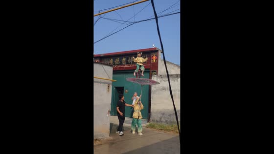 Young performer balances on unicycle atop umbrella in Hebei, China