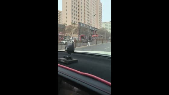 Woman loses balance while climbing over road barrier in Liaoning, China